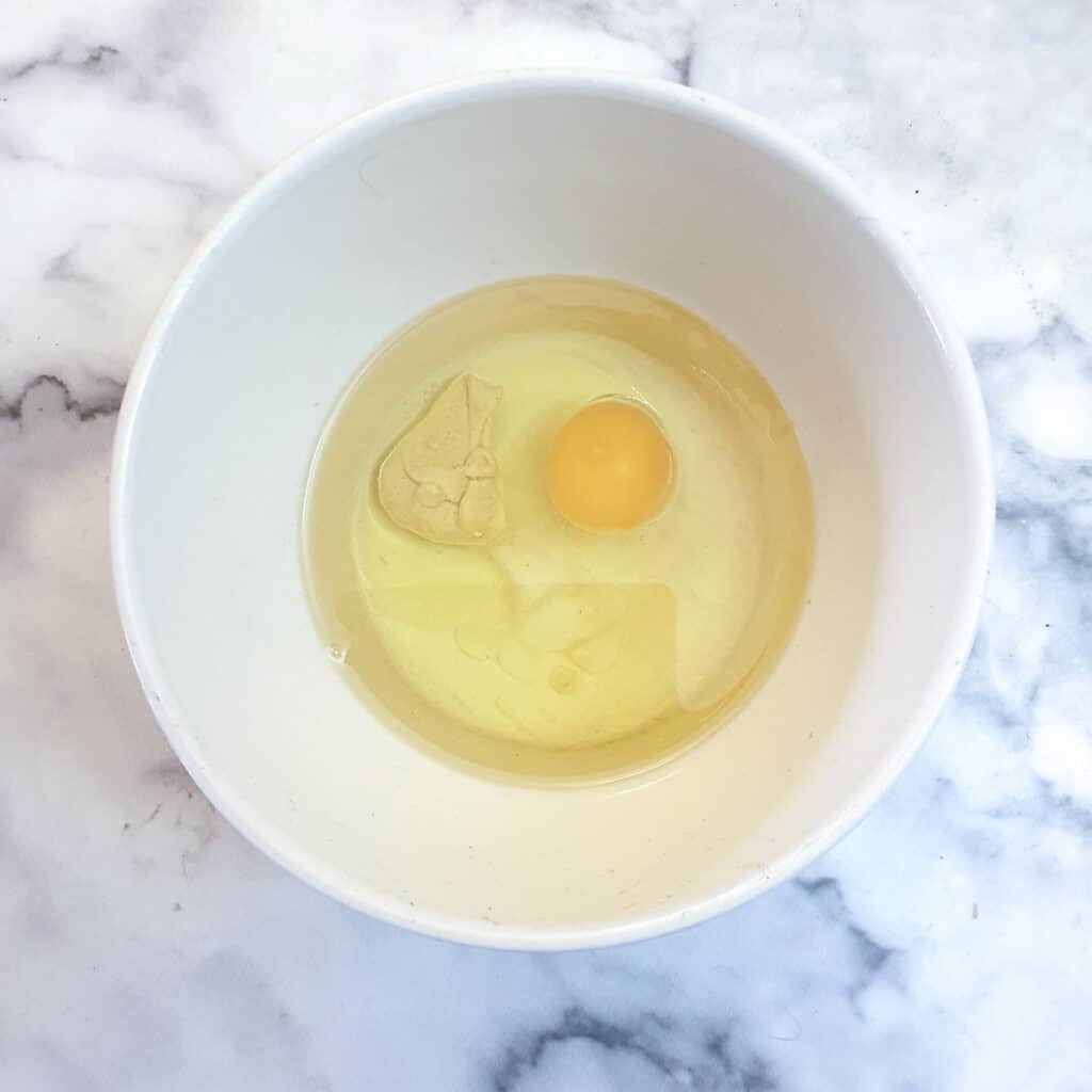 Oil and an egg in a mixing bowl.