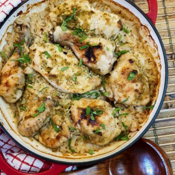 Overhead shot of Thai coconut chicken casserole in a red serving dish with a wooden serving spoon.