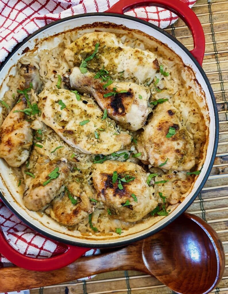 Overhead shot of Thai coconut chicken casserole in a red serving dish with a wooden serving spoon.