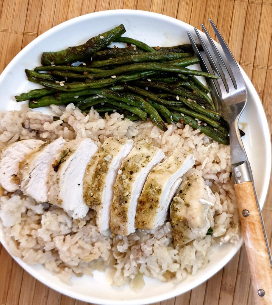 Chinese garlic green beans on a plate next to a Tha-flavooured chicken breast on a bed of coconut rice.