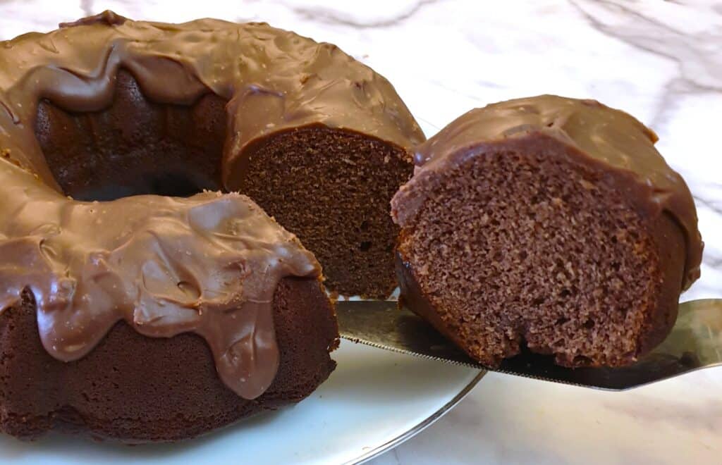 A slice of chocolate cake being cut from the bundt cake.