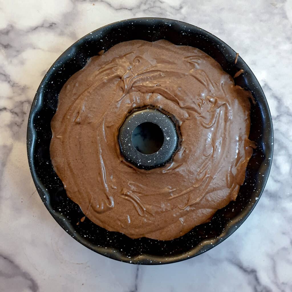 Chococlate cake batter poured into a round bundt pan.