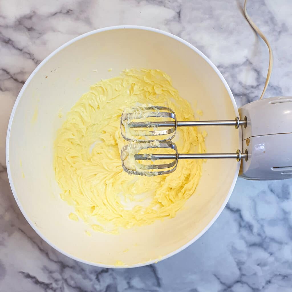 Butter being whisked by an electric hand-beater.