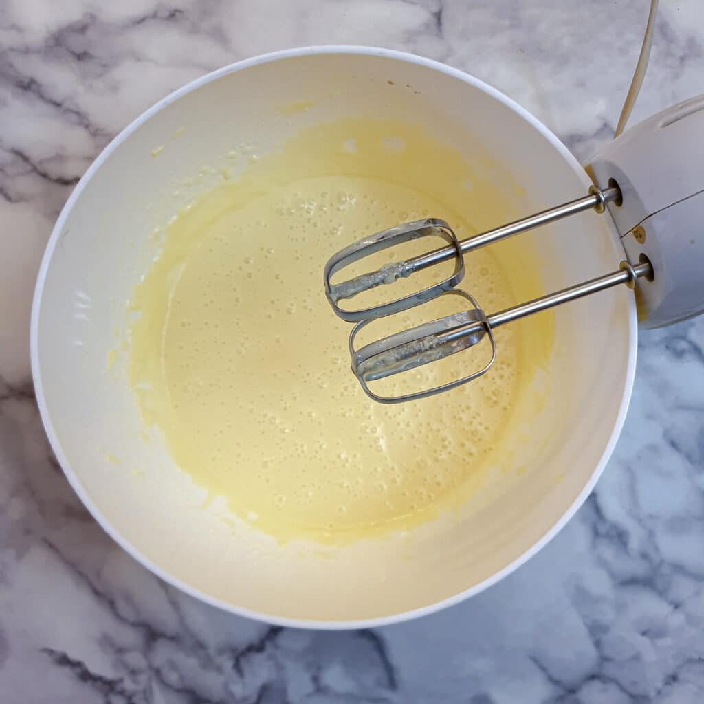 Condensed milk and butter beaten together in a white bowl.