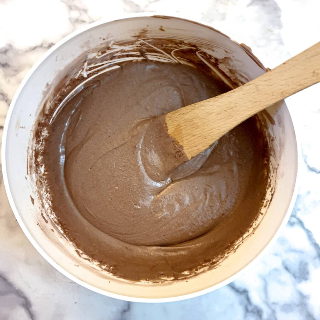 A white mixing bowl containing the chocolate cake batter.