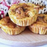 Three courgette and tomato puffs on a wooden board.