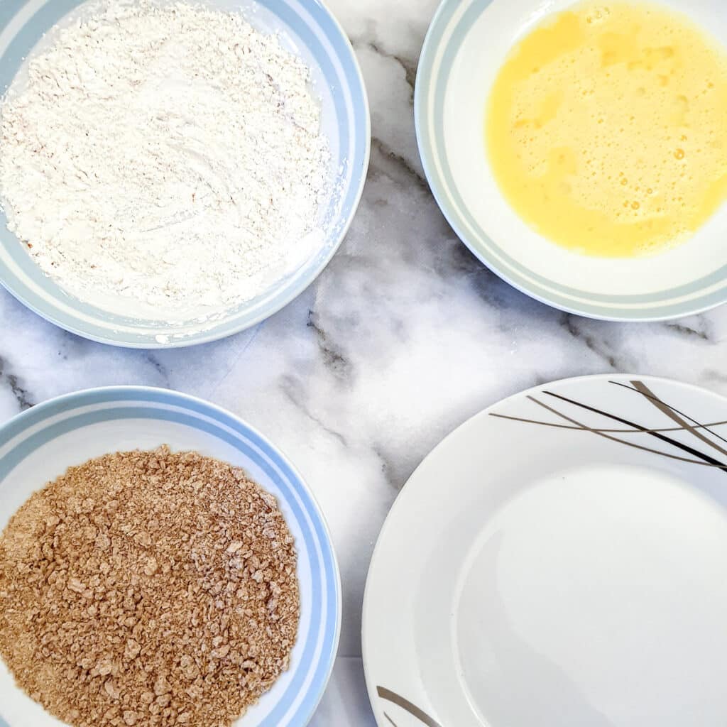 Dishes of flour, egg and breadcrumbs ready for coating the schnitzels.