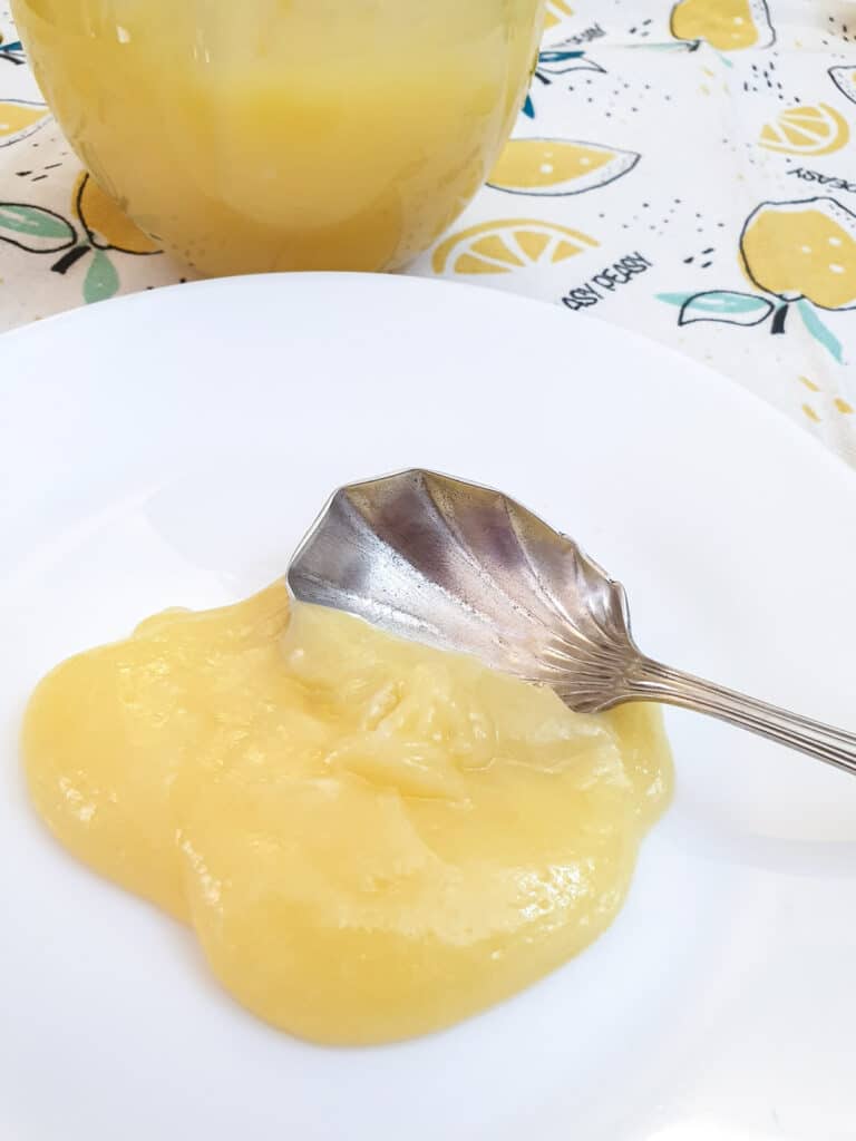 A spoonful of microwave lemon curd on a white plate.