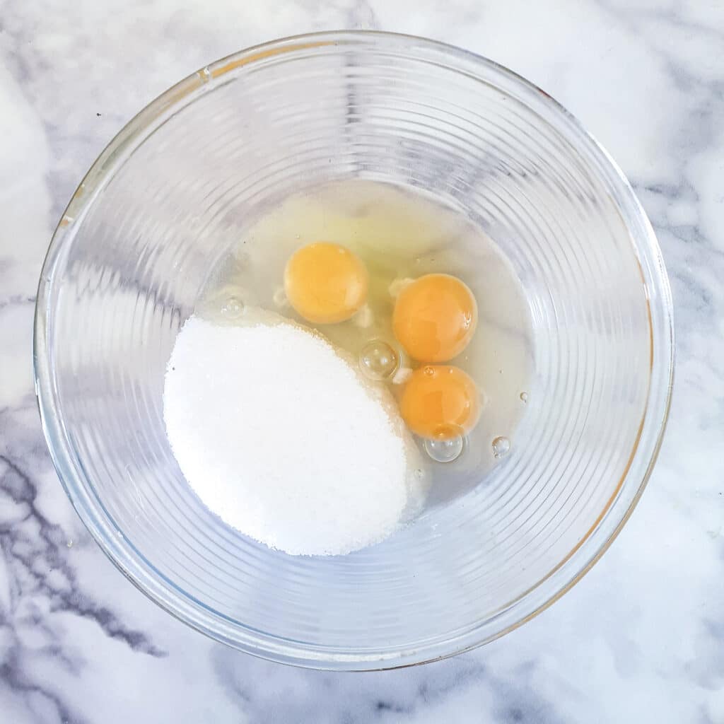 Eggs and sugar in a glass bowl.
