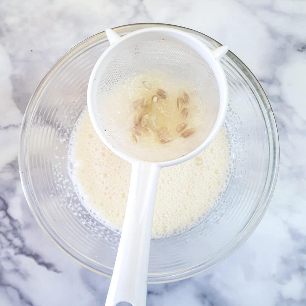 A small sieve held over a bowl to catch pips from lemon juice.