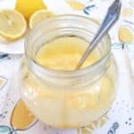Microwave lemon curd in a glass jar with a spoon.