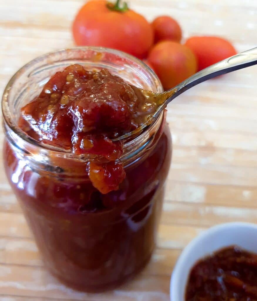 A jar of tomato jam with a spoonful being scooped out.