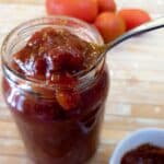 A jar of tomato jam with a spoonful being scooped out.
