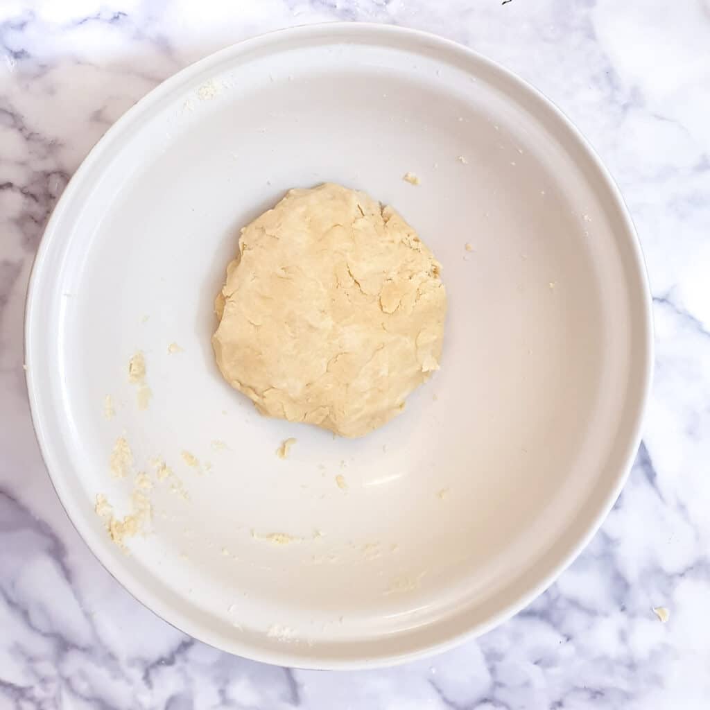 A ball of pastry in a mixing bowl.