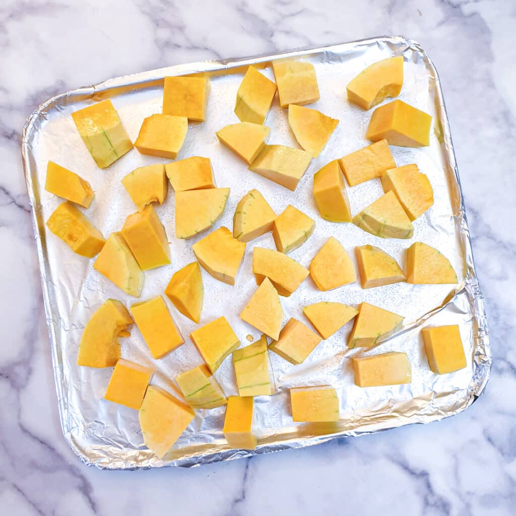 Raw butternut pieces on a baking tray.