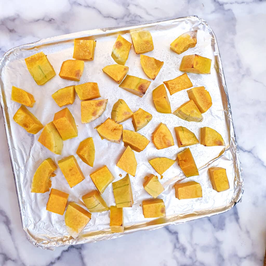 Roasted butternut pieces on a baking tray.