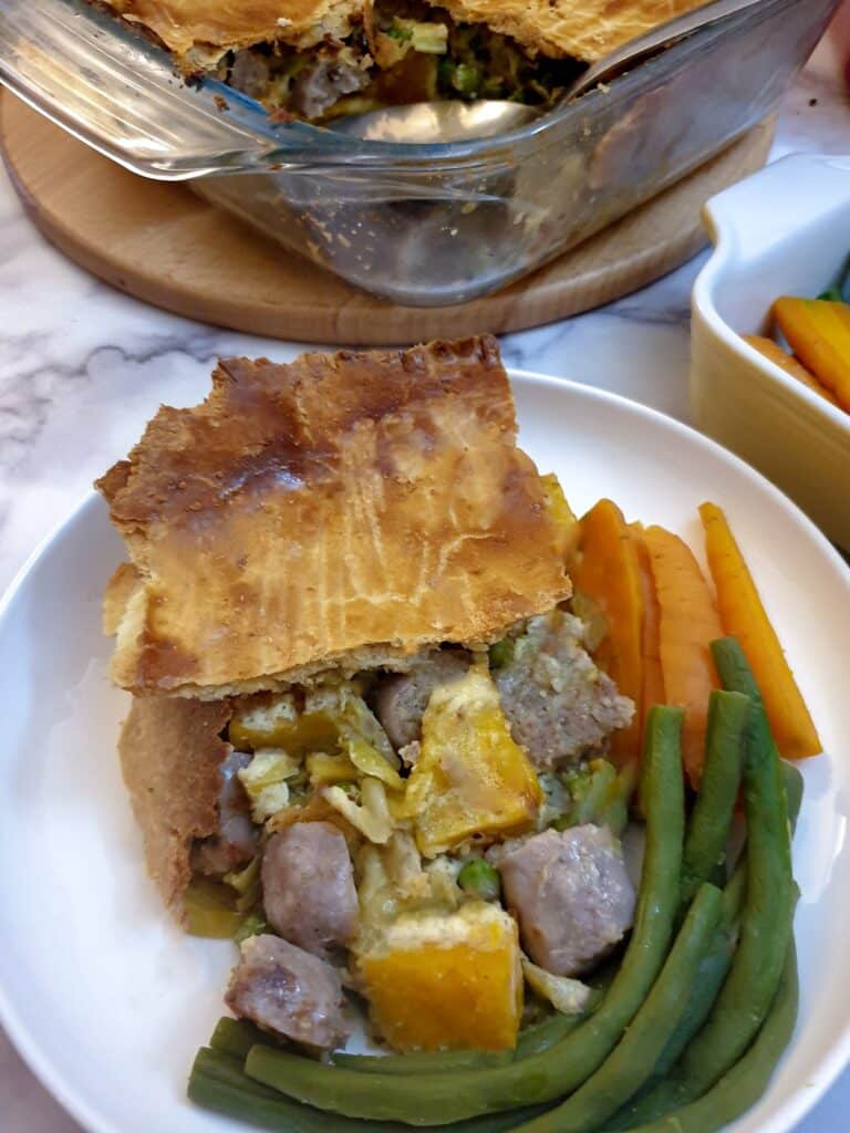 A slice of butternut and sausage pie with the pastry slightly off-set from the filling.