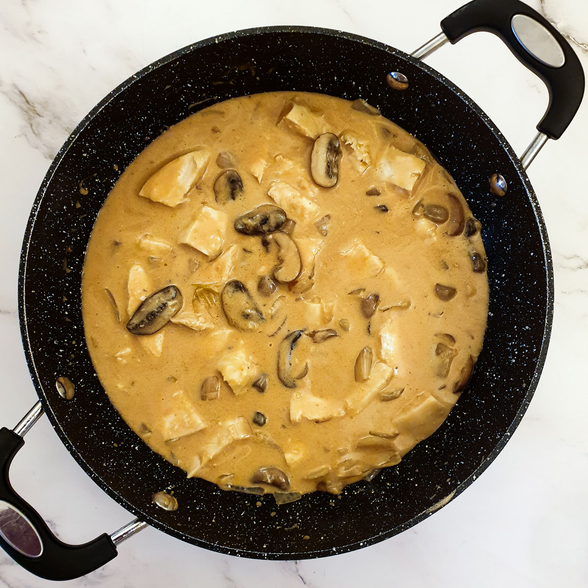 Chicken diane in a frying pan, after the cream has been added.