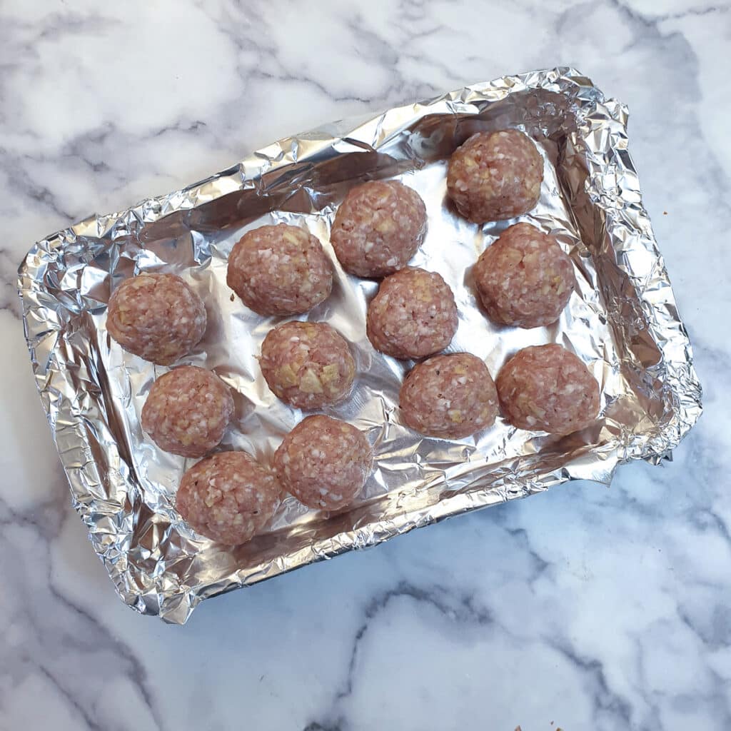 12 Halloween meatballs on a tin foil lined baking tray.