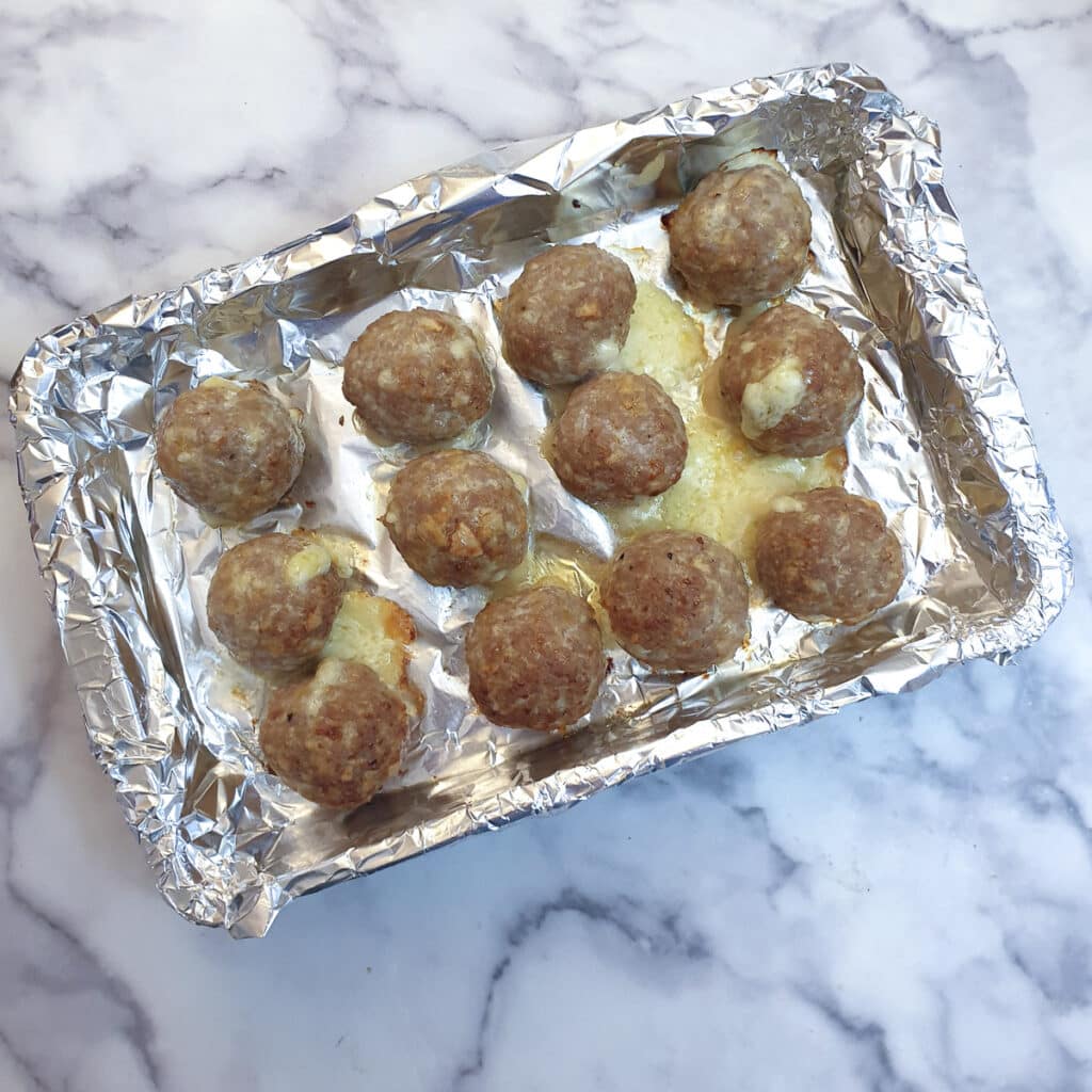 12 cooked meatballs on a baking tray.