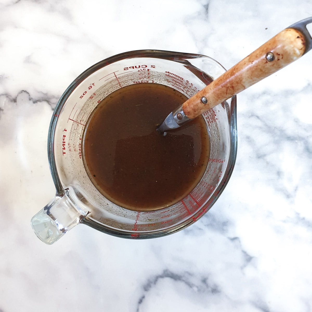 A glass jug containing gravy.