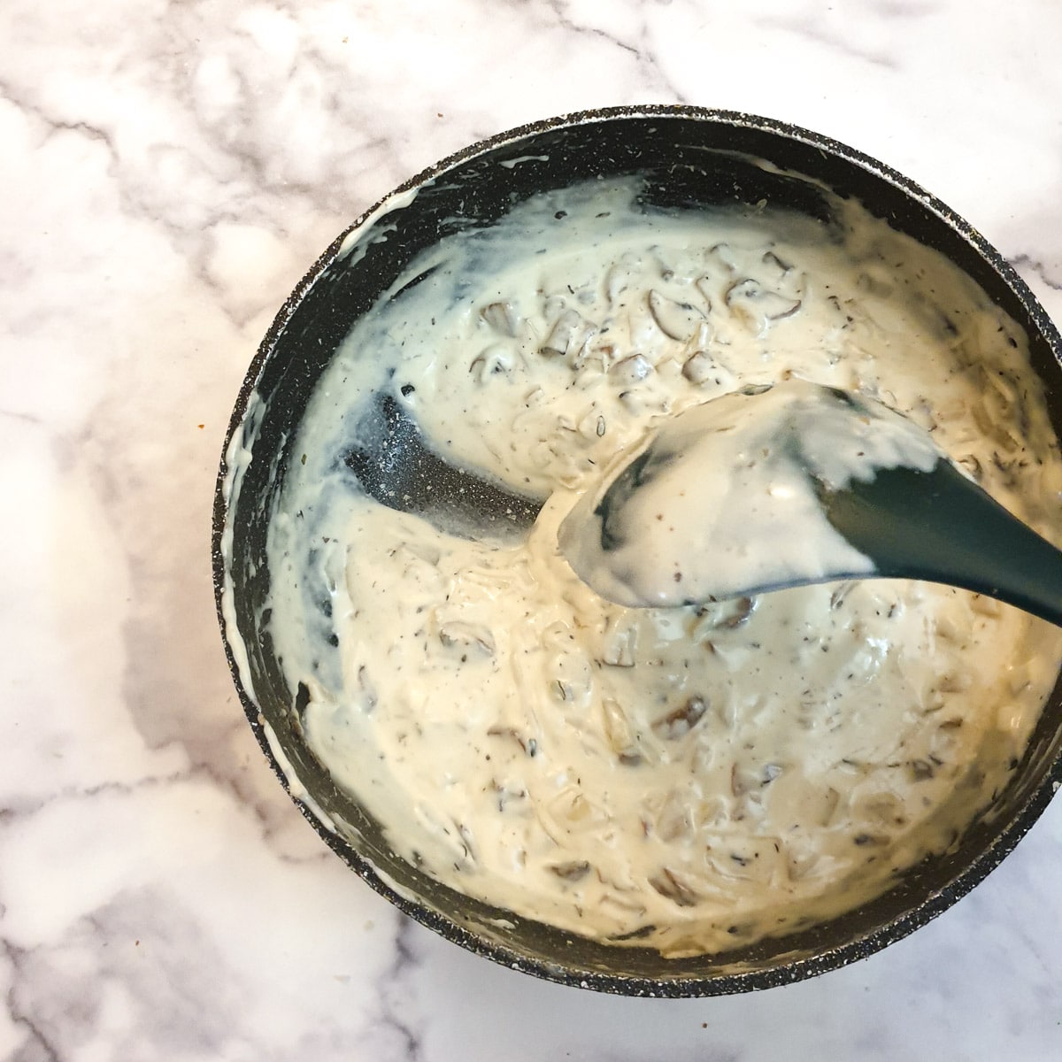 A spoon dragging a trail through the creamy sauce.