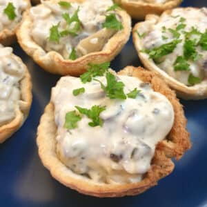 A plate of toasted mushroom breadcups garnished with chopped parsley.