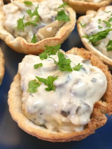 A plate of toasted mushroom breadcups garnished with chopped parsley.