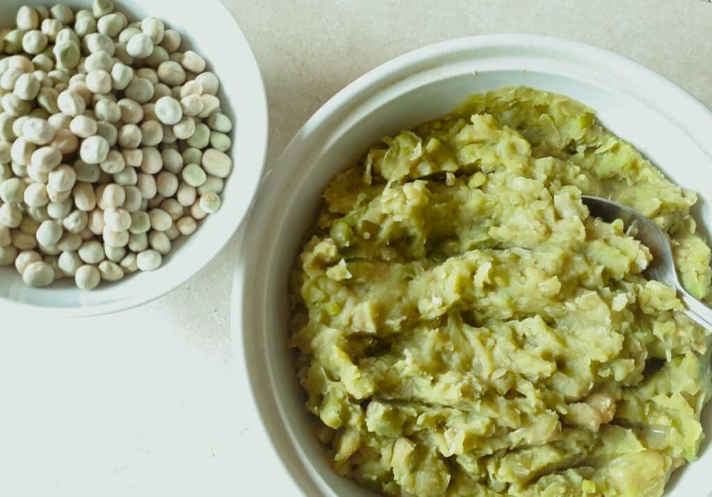 A bowl of cooked mushy peas next to a bowl of dried marrowfat peas.