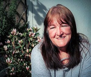 A picture of Veronica in the garden in front of a pink-flowering shrub.