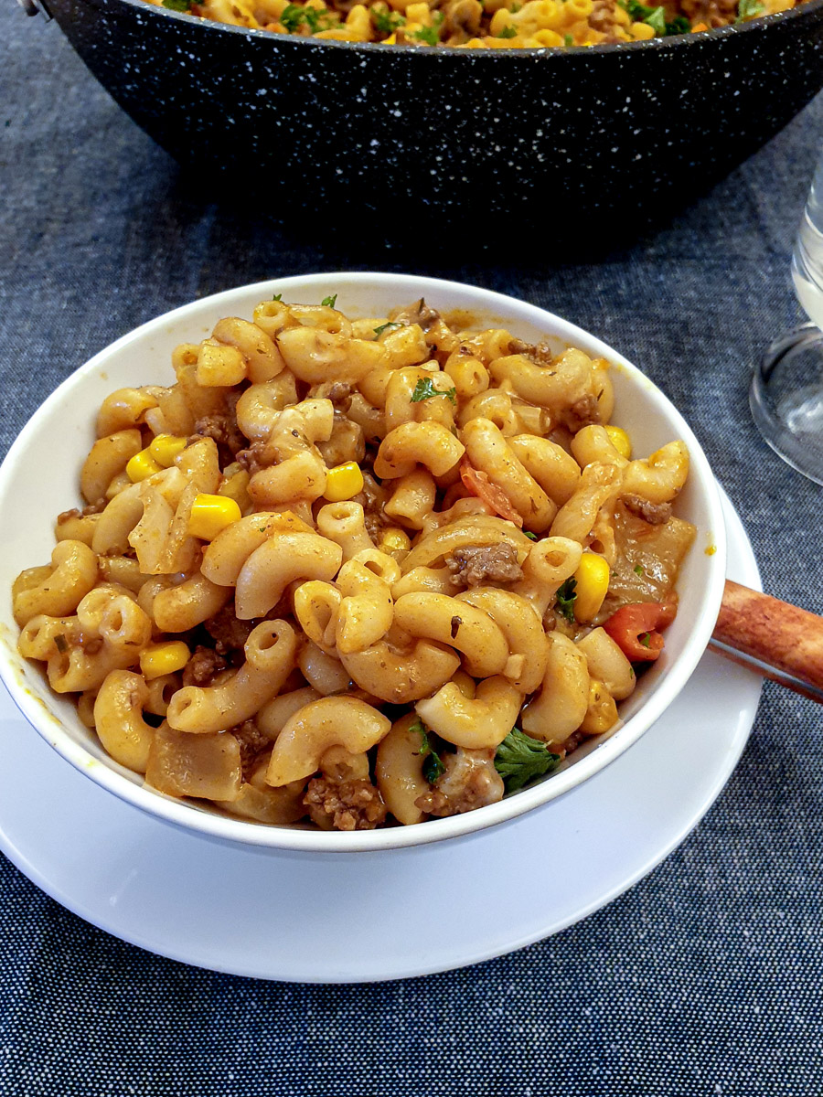 A white serving bowl filled with American goulash.