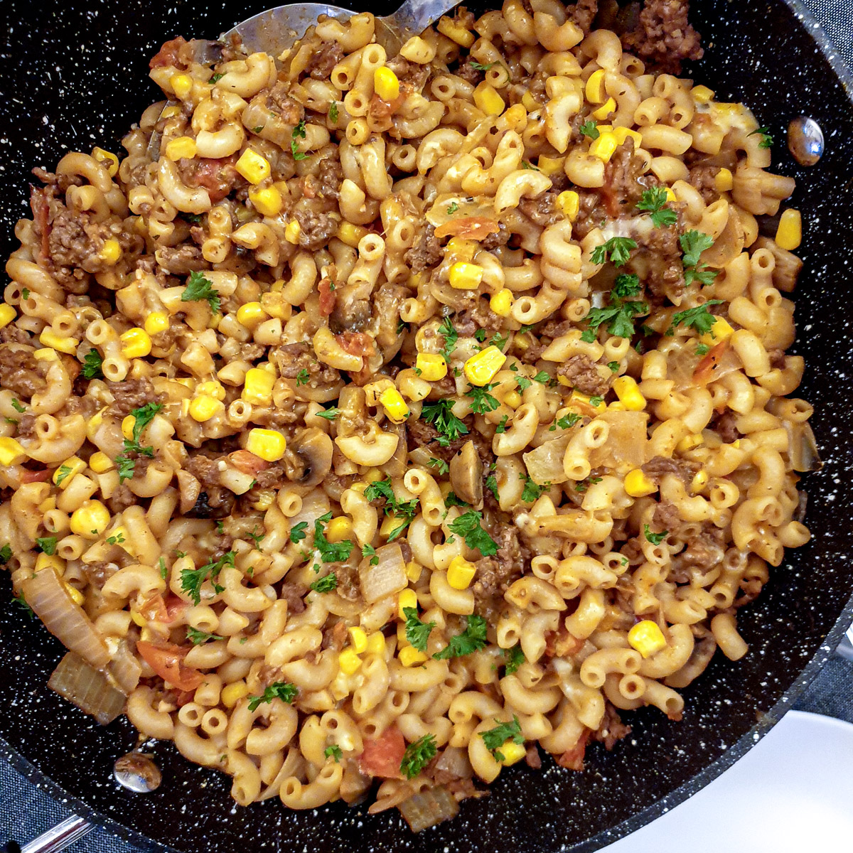 Corn and cheese stirred into the goulash, with chopped parsley sprinkled on top.