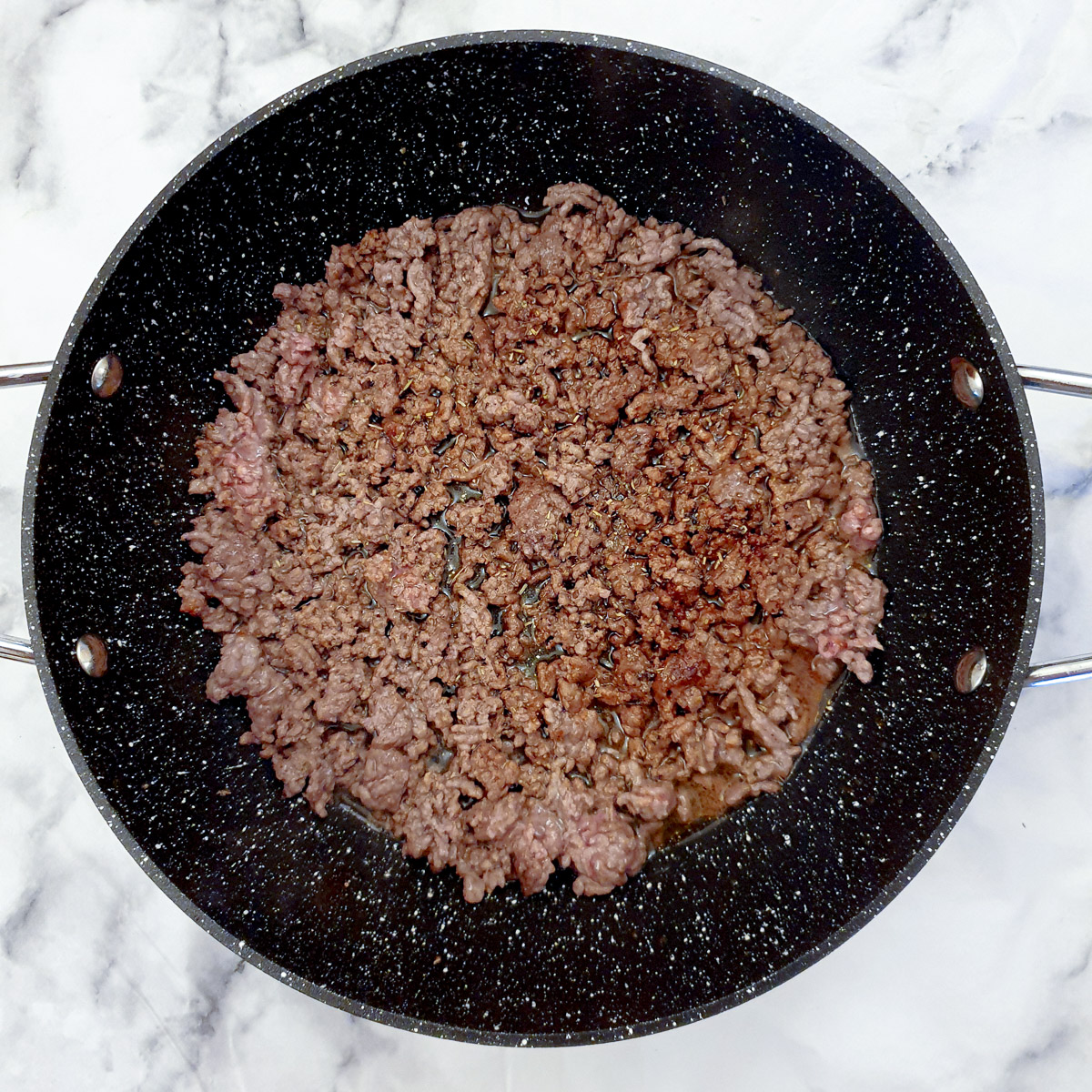 Ground beef browning in a black frying pan.