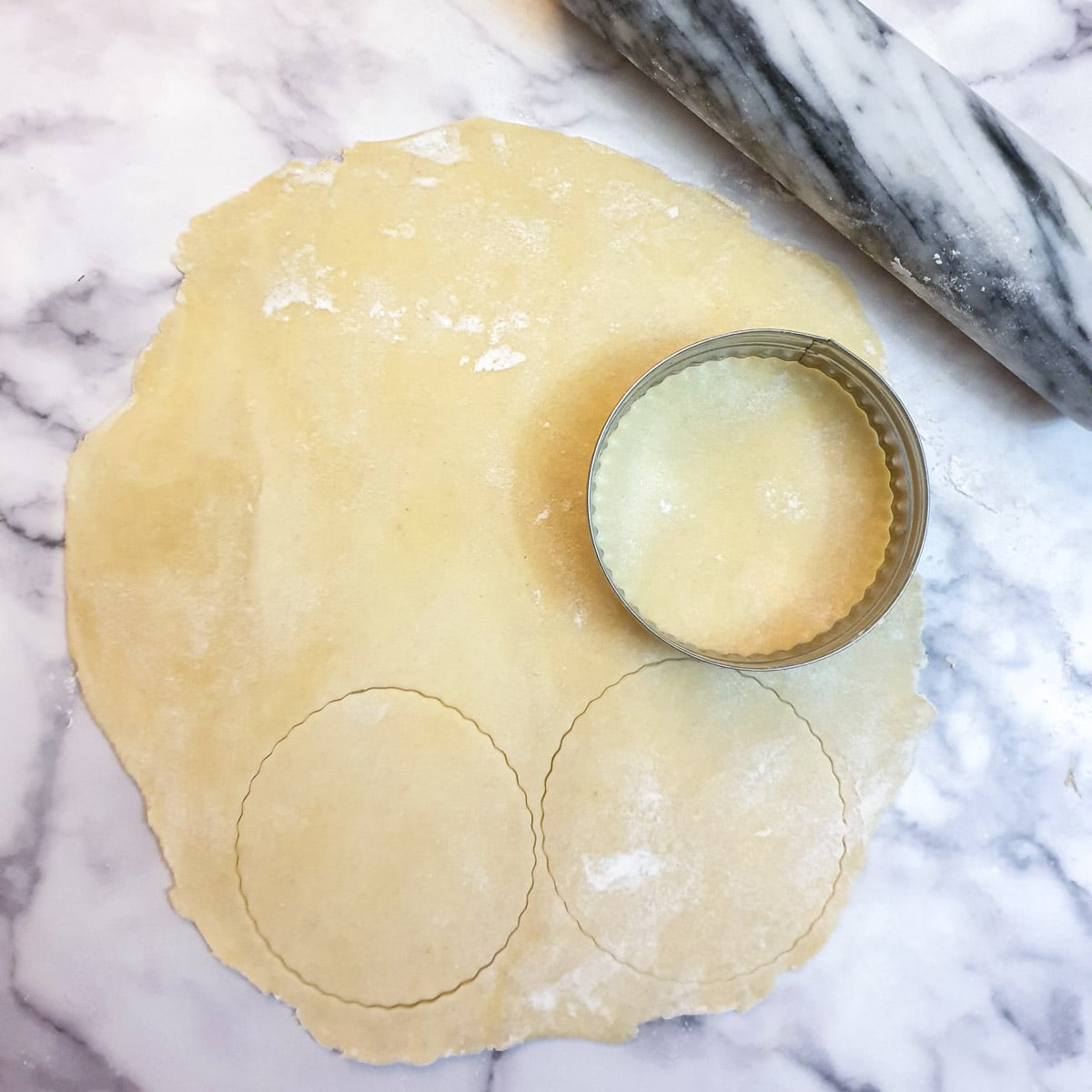 Circles of pastry being cut from a rolled sheet of dough.