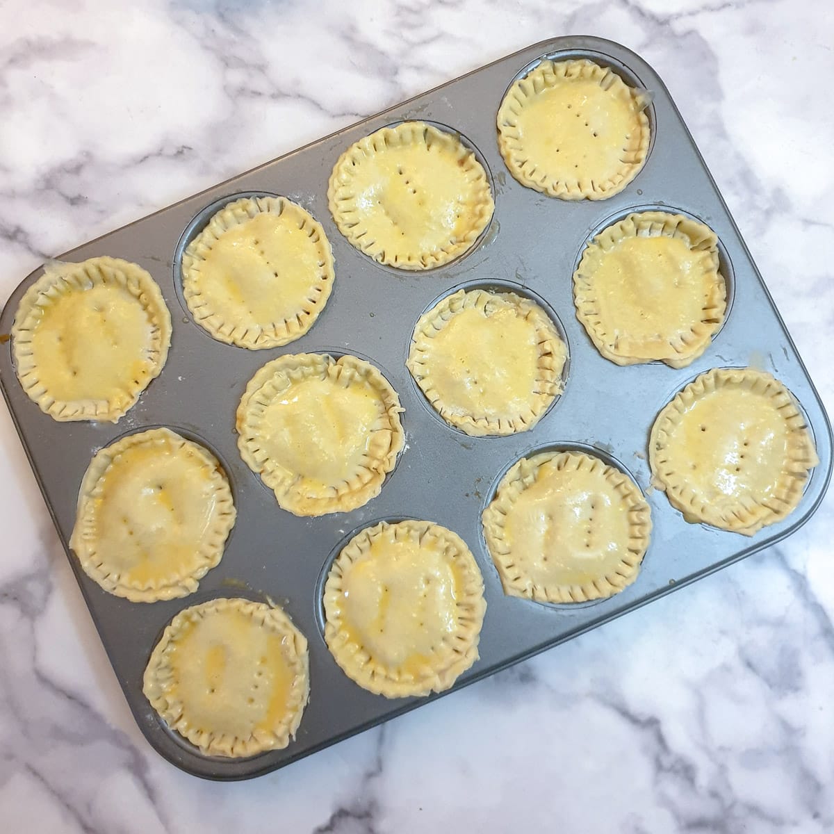 12 unbaked pies in a muffin tin.