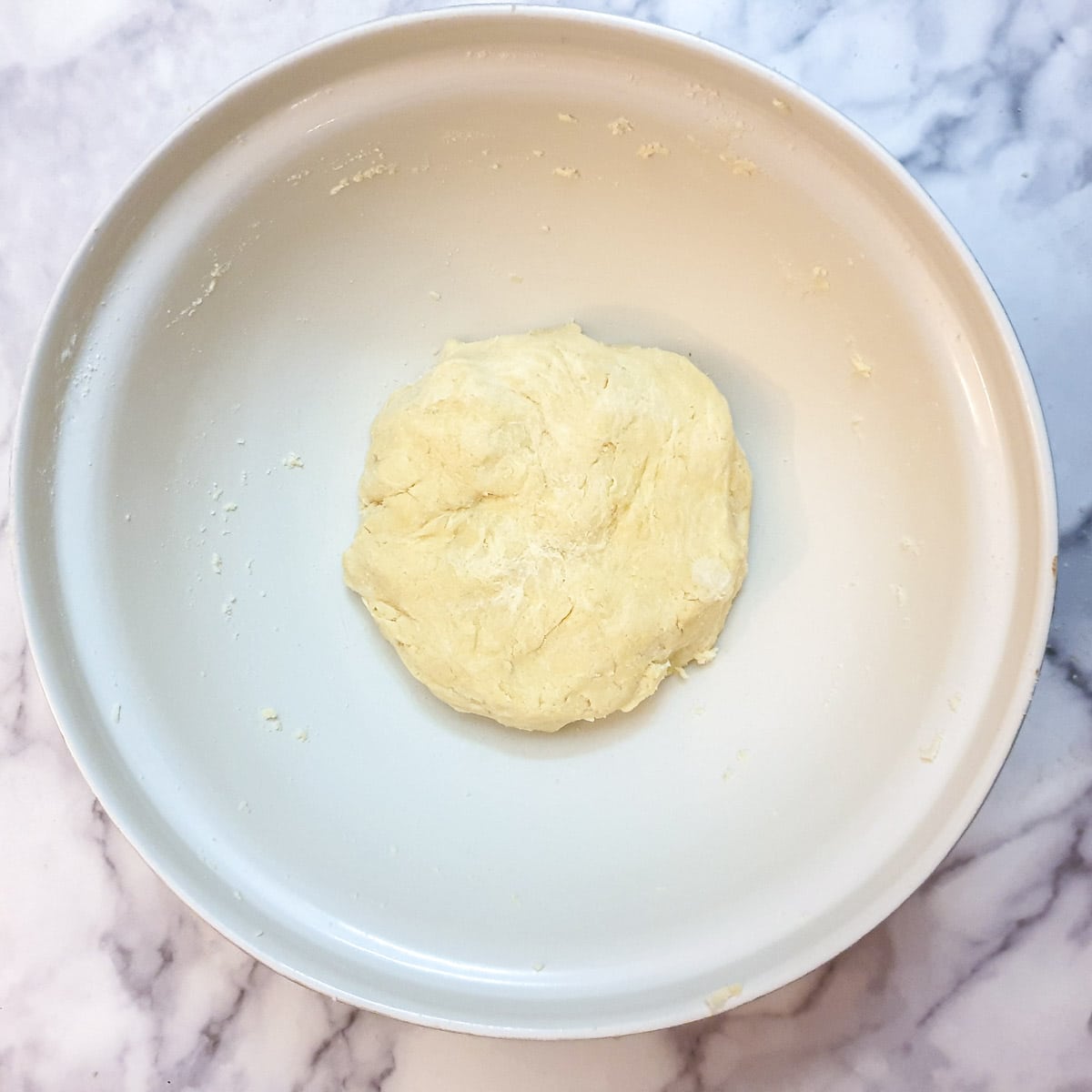 A ball of dough in a large white mixing bowl.