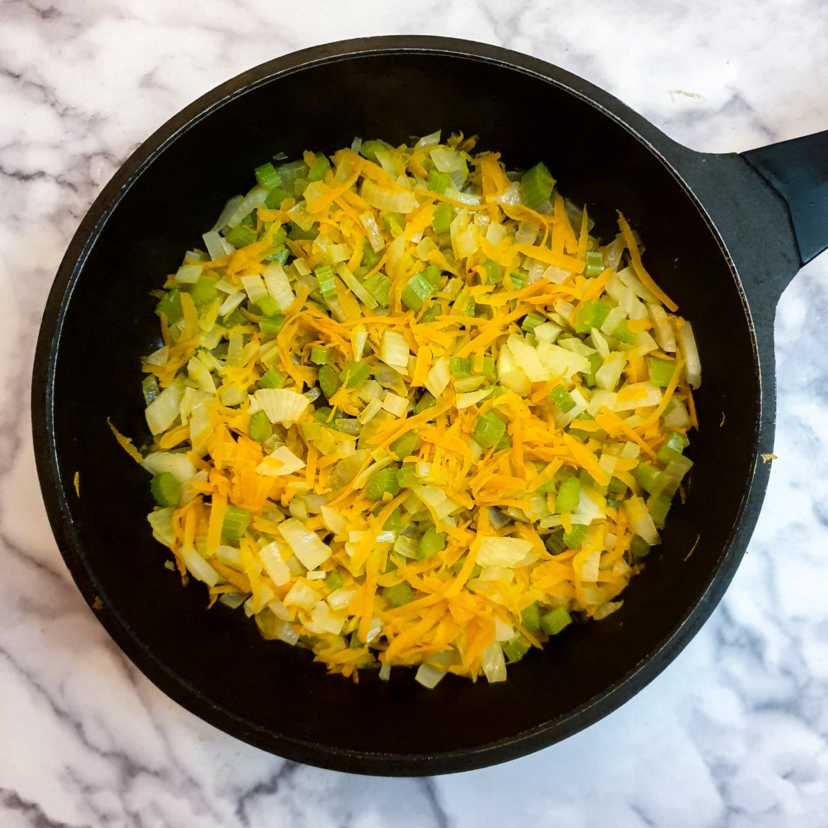 Diced onions, celery and carrots softening in a frying pan.