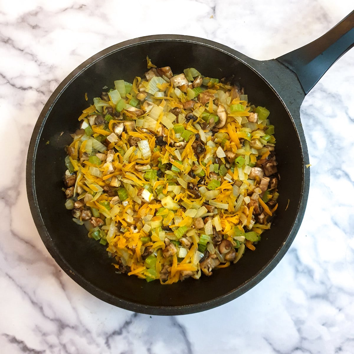 Mushrooms cooking with a mirepoix of carrots, onions and celery.