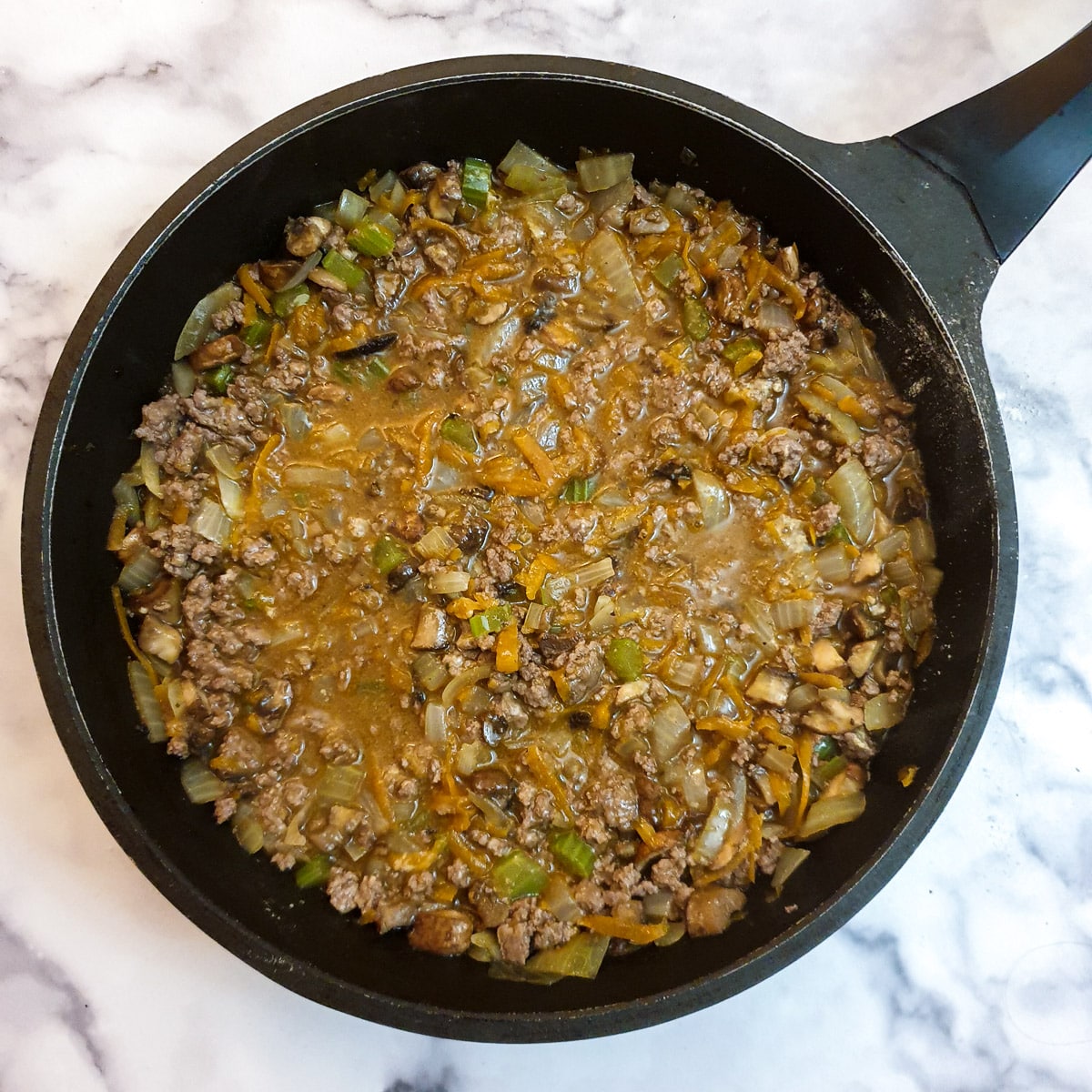 A frying pan containing filling for beef and onion hand pies.