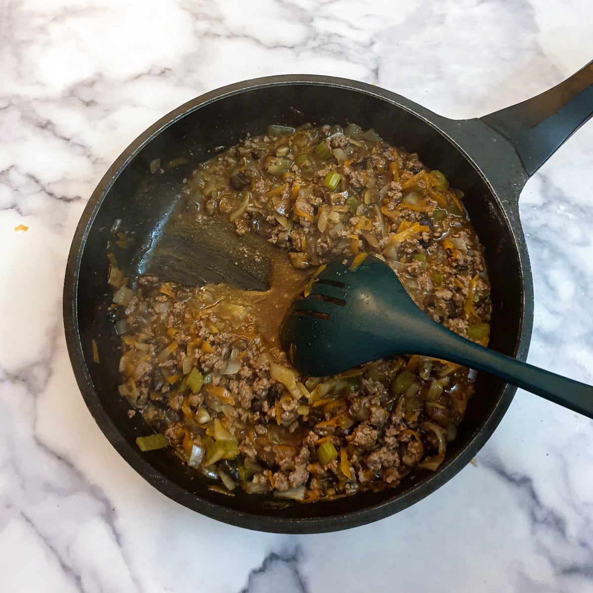 A spoon being drawn through meat filling, showing the consistency.