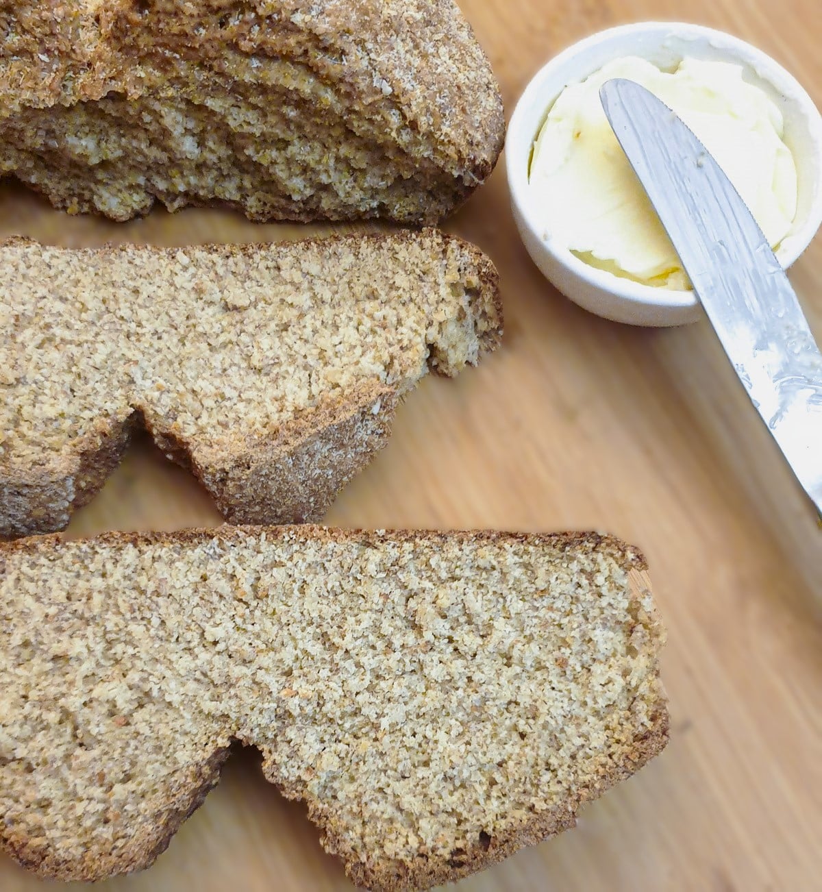 2 slices of unbuttered soda bread with a dish of butter and a knife.