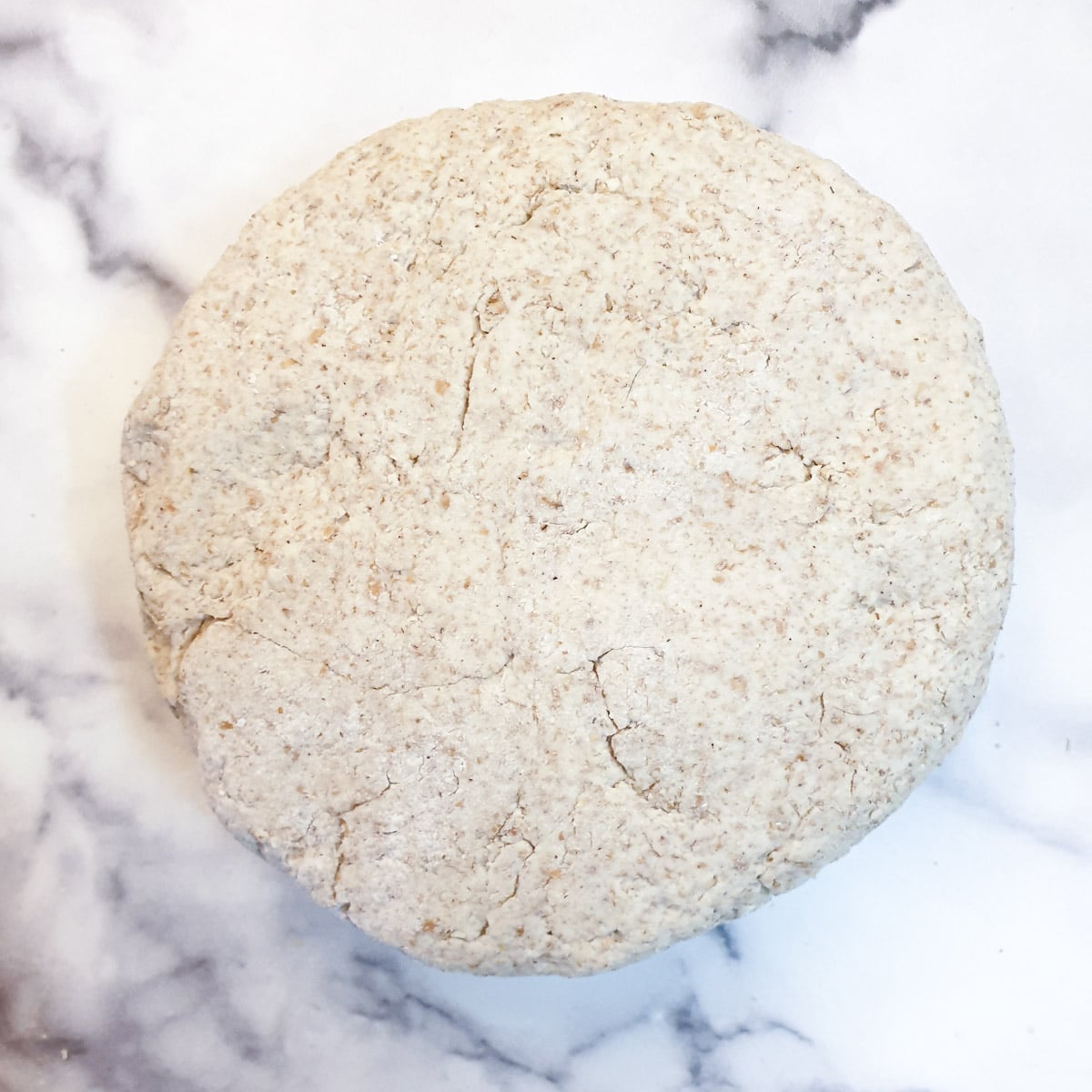 A round disk of dough on a work surface.