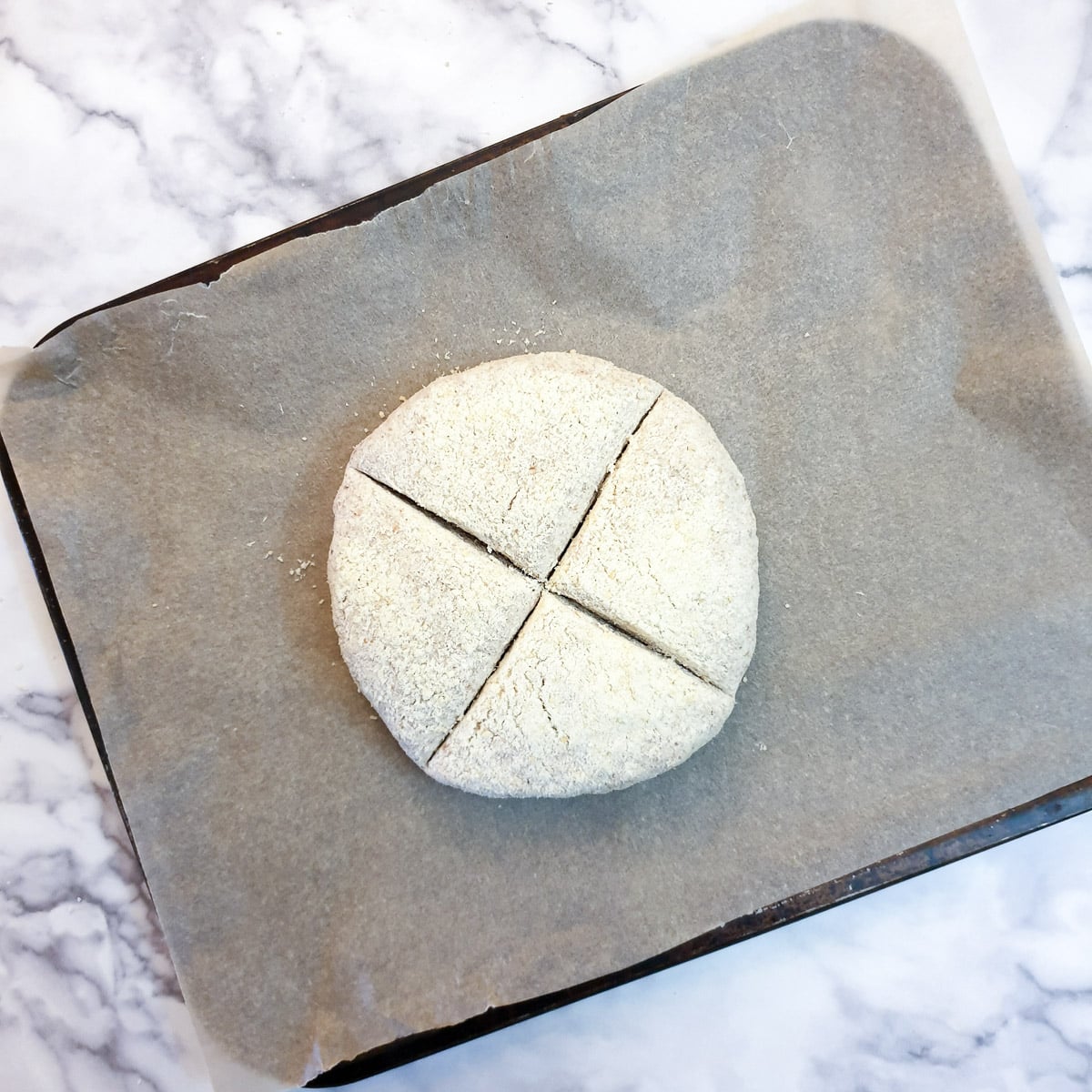 Soda bread on a baking tray, with a cross marked in the top.