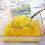 A spoonful of ghee held over a dish.