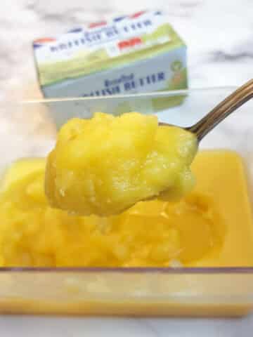 A spoonful of ghee held over a dish.