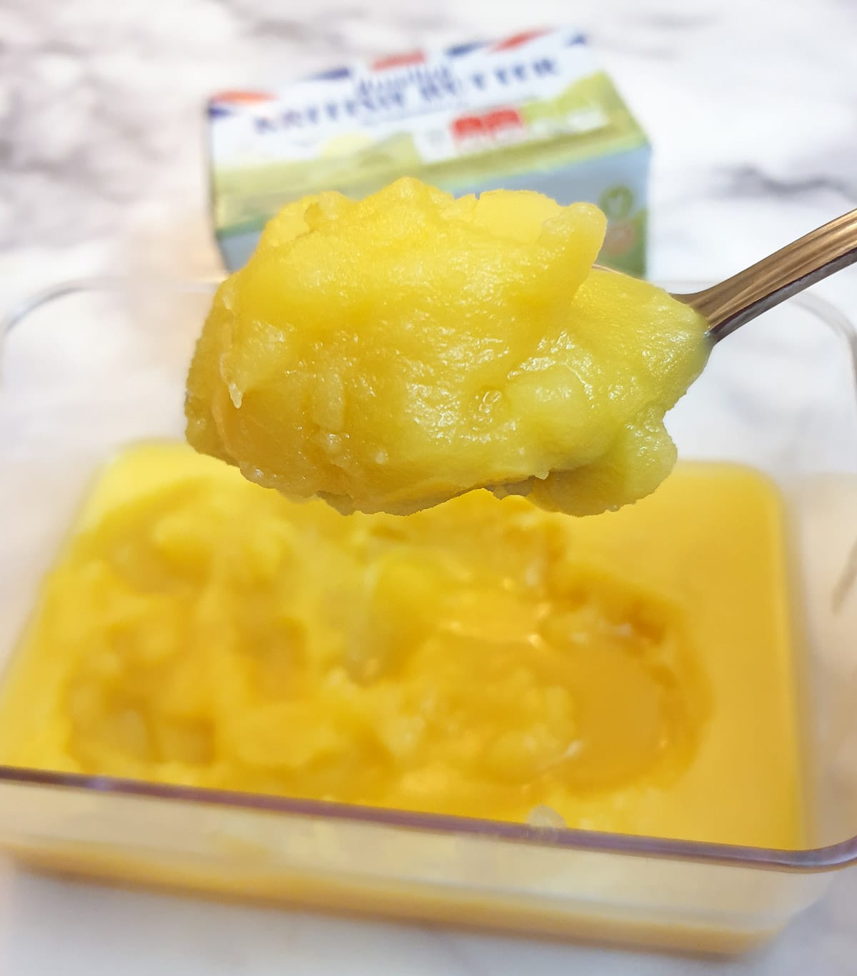 A spoonful of ghee held over a dish.