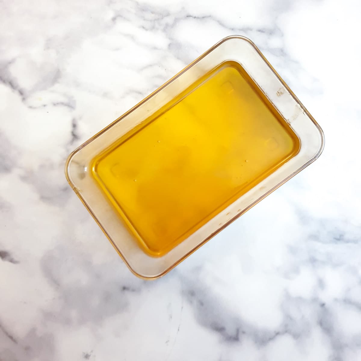 A rectangular glass container holding melted ghee.