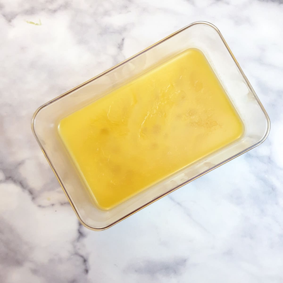 A rectangular glass container holding solidified ghee.