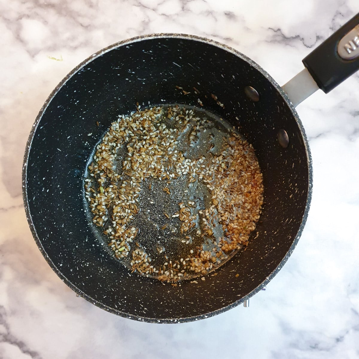 Crushed garlic, cumin and sesame seeds frying in ghee.