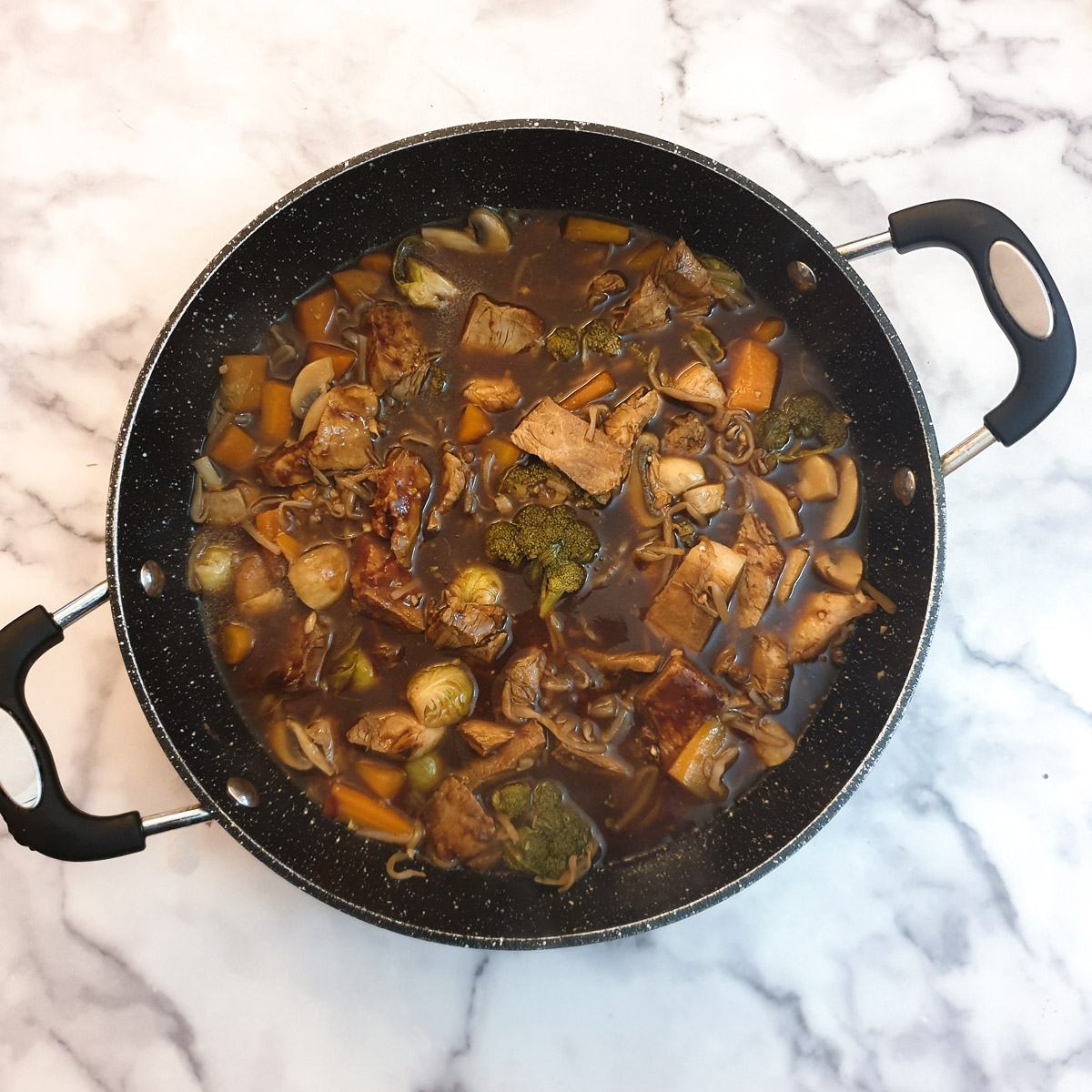 Overhead shot of the completed dish of leftover roast pork in garlic sauce in a frying pan.